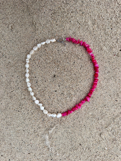 Necklace with corals and freshwater pearls on a sandy surface